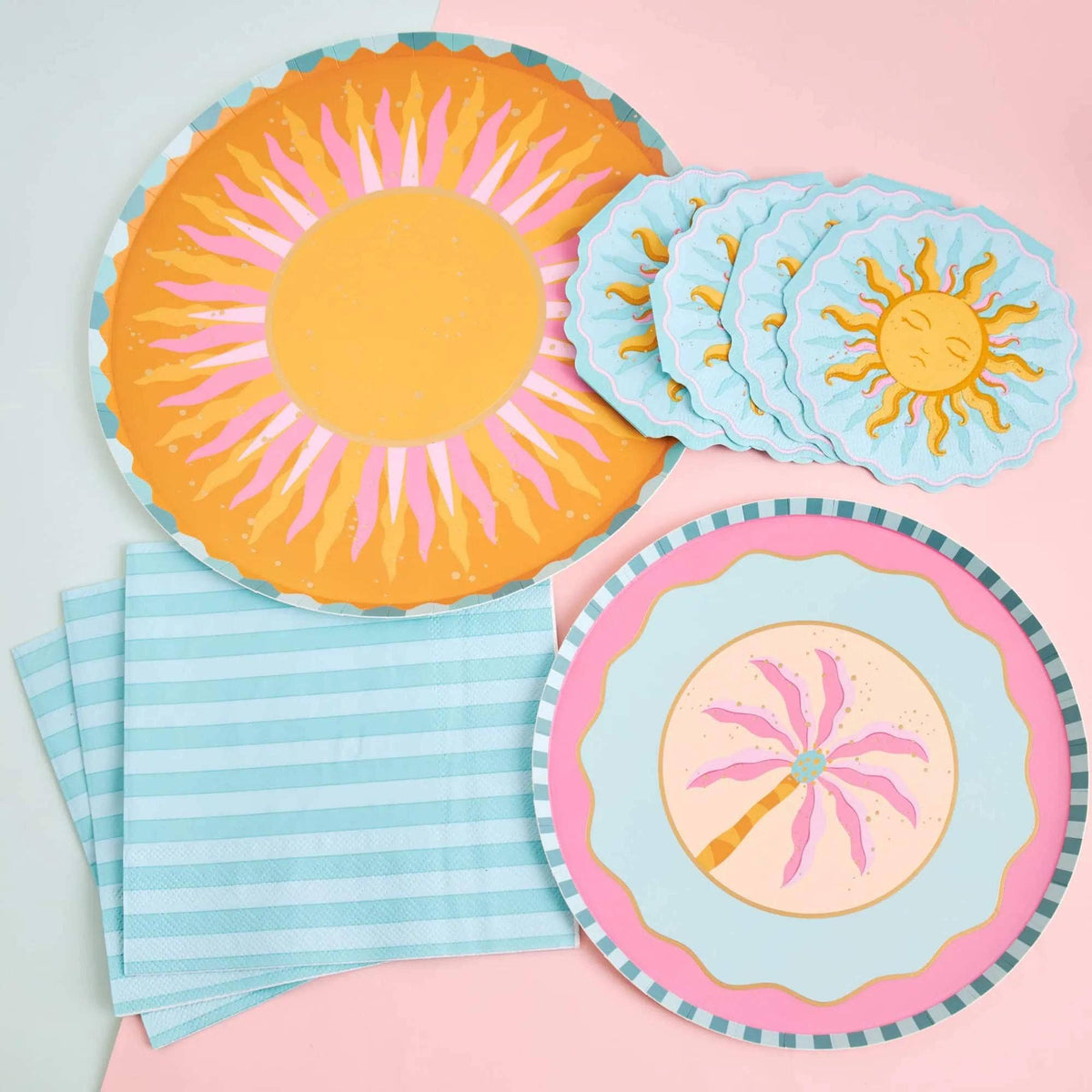 Orange and pink sunburst paper dinner plates angled in a group, showing the golden center and teal scalloped edge.