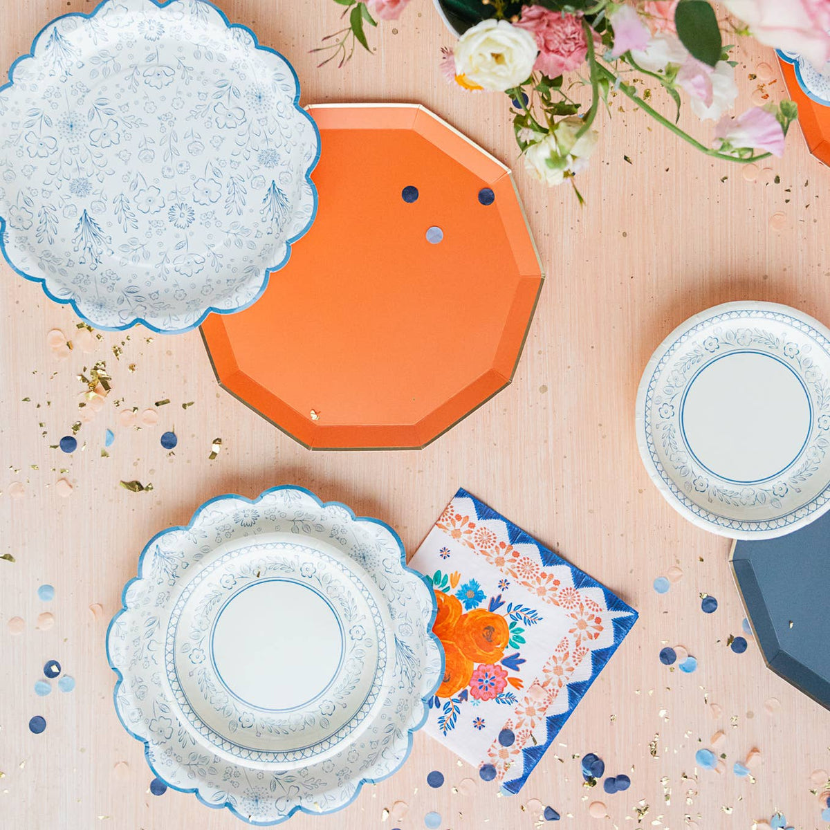 Mixed tableware spread with Sunkissed Orange plate and blue floral plates at spring celebration