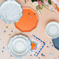 Mixed tableware spread with Sunkissed Orange plate and blue floral plates at spring celebration