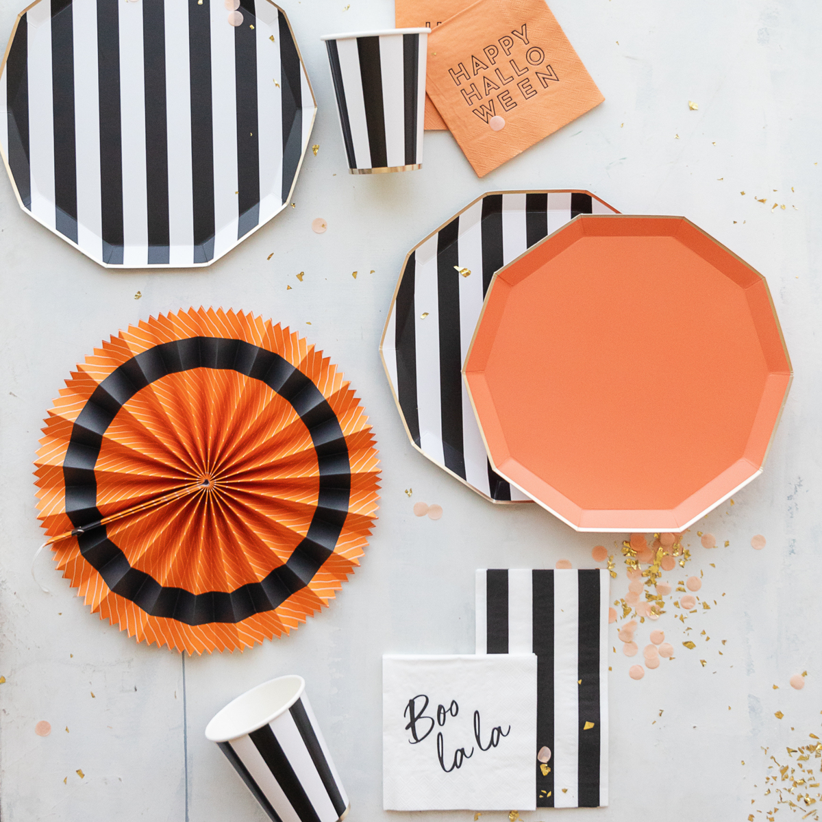 Orange plate and striped black-and-white plates in Halloween party table setup
