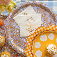 Flat lay of floral serving trays with a stack of Thanksgiving napkins and cupcakes.