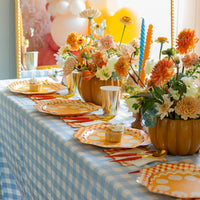 Blue-gingham tablescape with pumpkin centerpieces and gold-rim pumpkin pie plates at each setting.