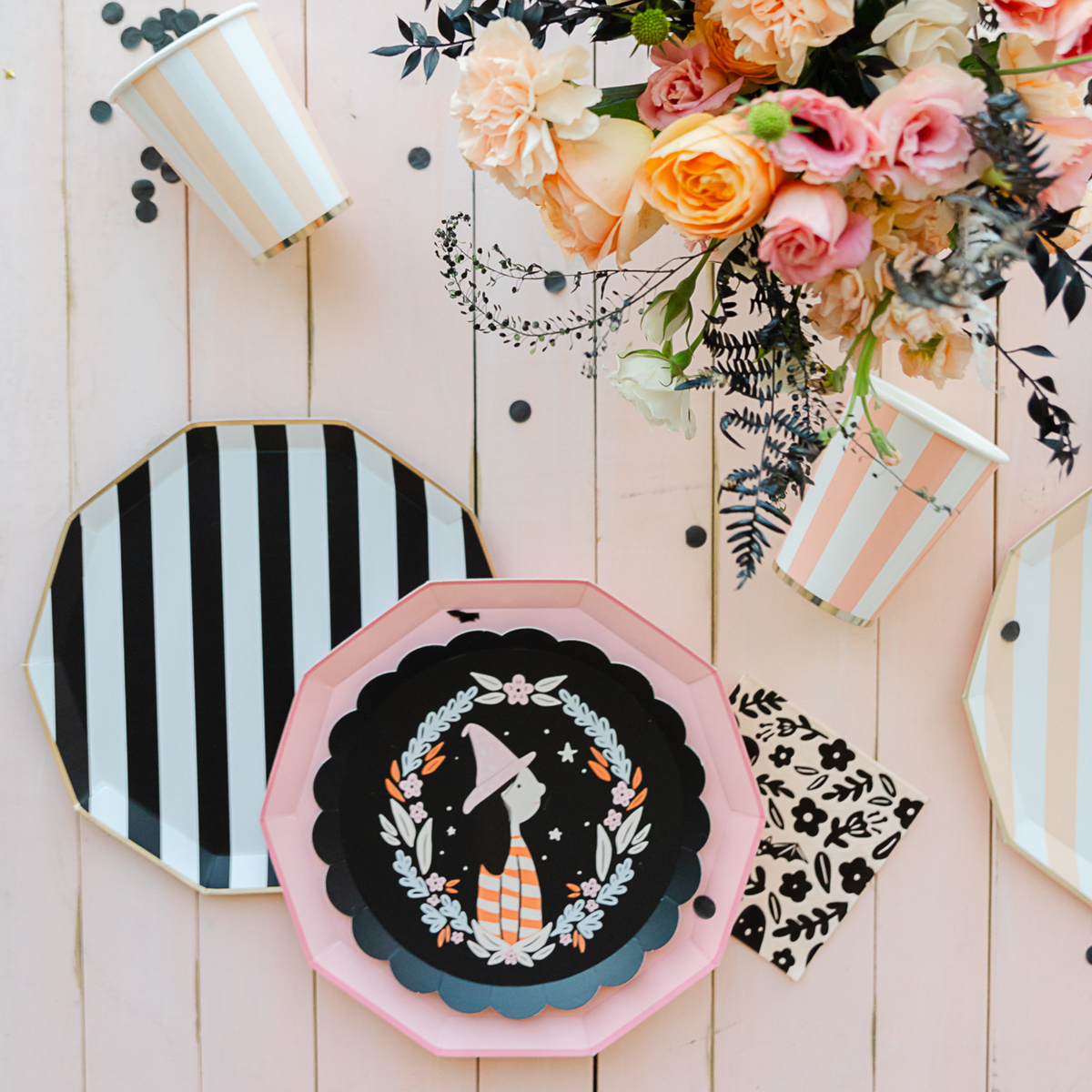 Peach cabana stripe cup on pink wood table with floral arrangement