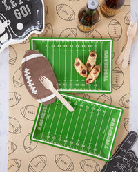Football table runner styled with field trays, a football napkin, wooden forks, and soda bottles