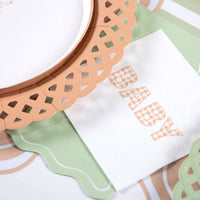 Close view of a tan gingham BABY napkin next to a tan lattice charger and a sage scalloped napkin