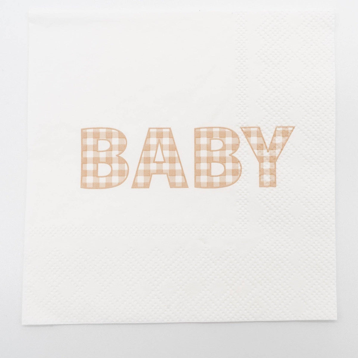 Flat overhead of a tan gingham BABY paper cocktail napkin unfolded on white