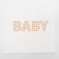 Flat overhead of a tan gingham BABY paper cocktail napkin unfolded on white