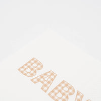 Close crop of the BABY lettering in tan gingham print on a white paper napkin