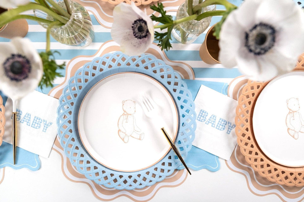 Tan teddy bear plates at two settings with white anemones, gold flatware, and blue gingham napkins