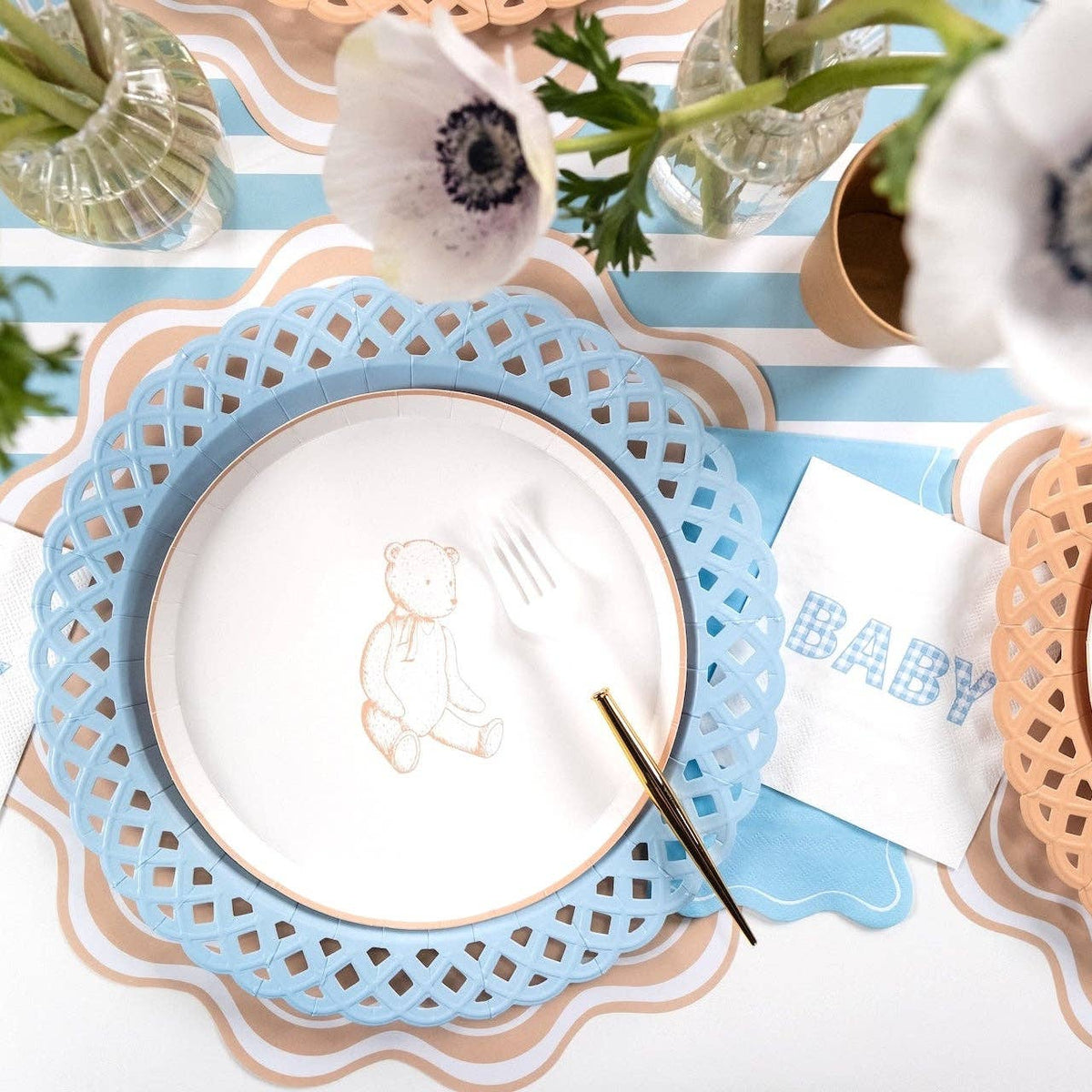 Tan teddy bear paper plate on a blue lattice charger with a blue gingham BABY napkin and white anemones