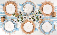 Six place settings with tan teddy bear plates on alternating blue and tan chargers with kraft cups