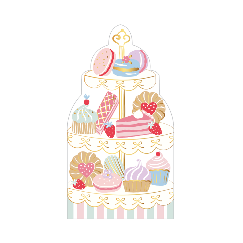 Die-cut tea party napkin shaped like a tiered patisserie dessert tower stacked with macarons, cakes, and cupcakes in pastel and gold, front view on white background.