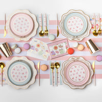 Styled tea party place setting showing the tower napkins with scalloped plates, gold flatware, and pastel décor on a striped runner.