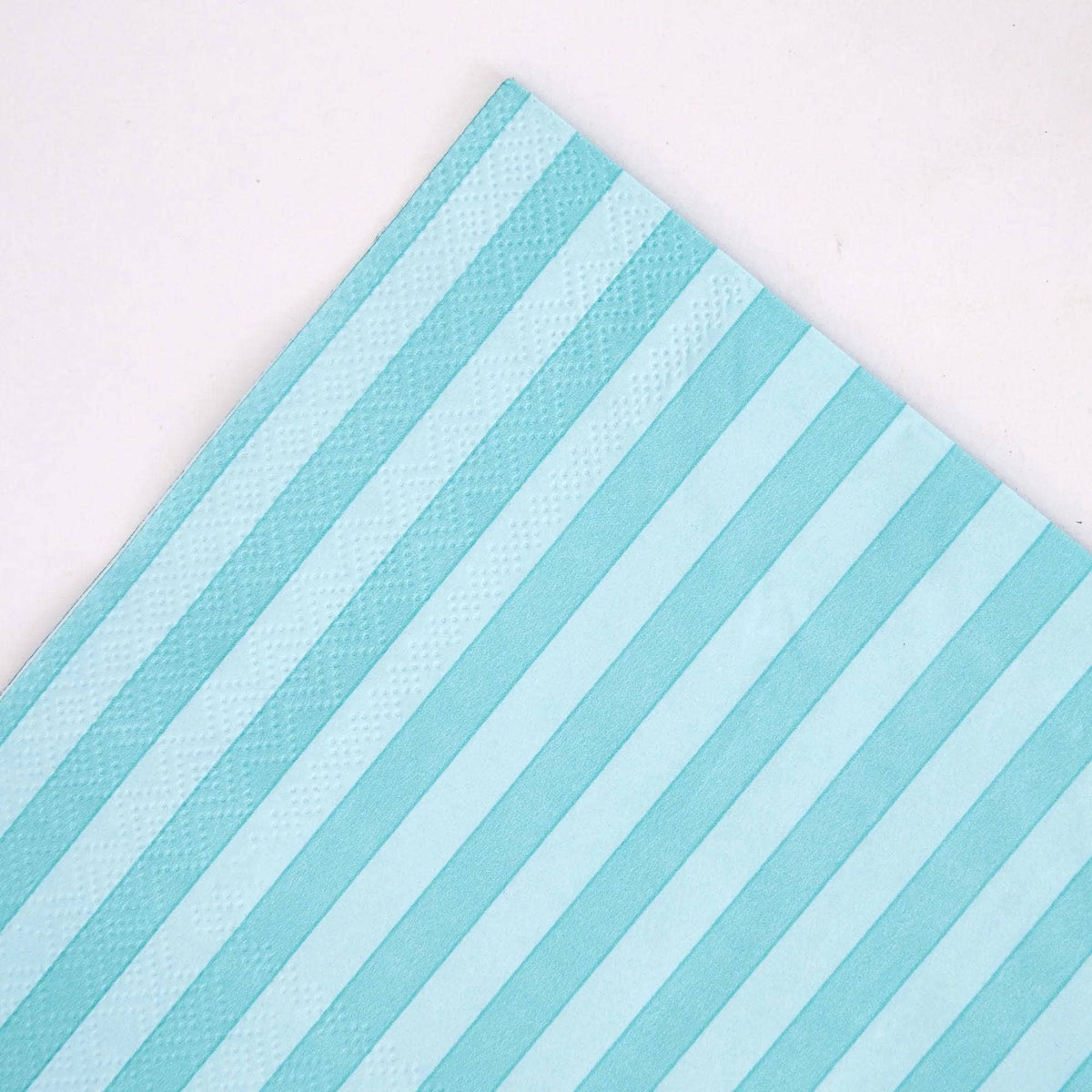 Angled corner detail of teal striped paper napkin