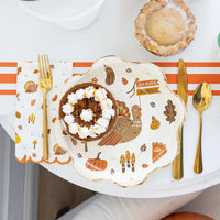 Thanksgiving place setting with icons plate, gold flatware, and mini pie.