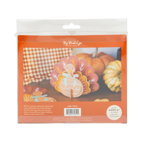 Package of a turkey craft kit with pumpkins and checkered tablecloth in the background, back view.