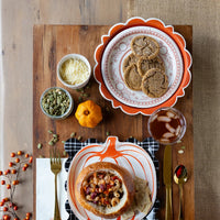 Rustic Thanksgiving place setting featuring Happy Harvest pumpkin paper plates, autumn napkins, seasonal soup, and harvest table decor.