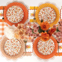 Overhead fall table set for four with lattice chargers, floral plates, and scalloped cocktail napkins at each seat
