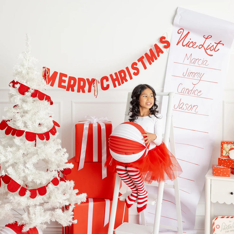 Close-up vignette of tree and gifts with the felt Merry Christmas banner draped across the wall.