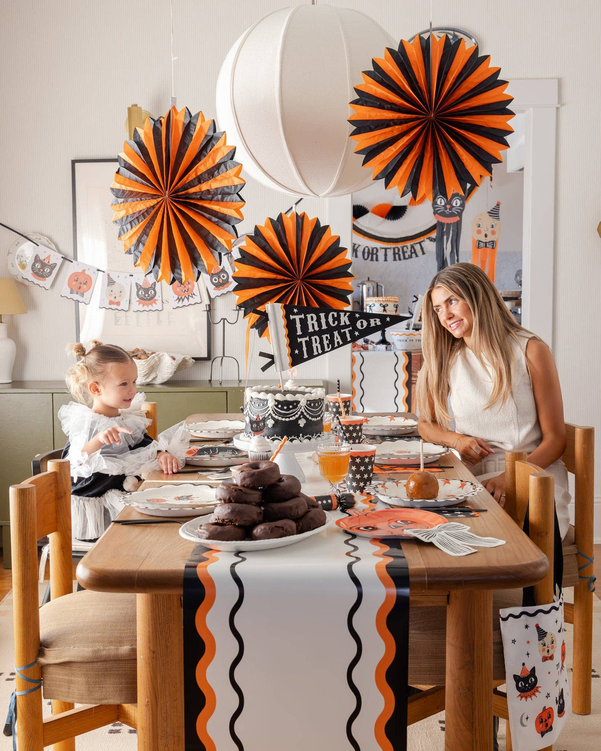 Woman and child sitting at a Halloween-themed dining table with the Vintage tissue fans. 