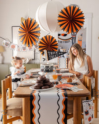 Woman and child sitting at a Halloween-themed dining table with the Vintage tissue fans. 