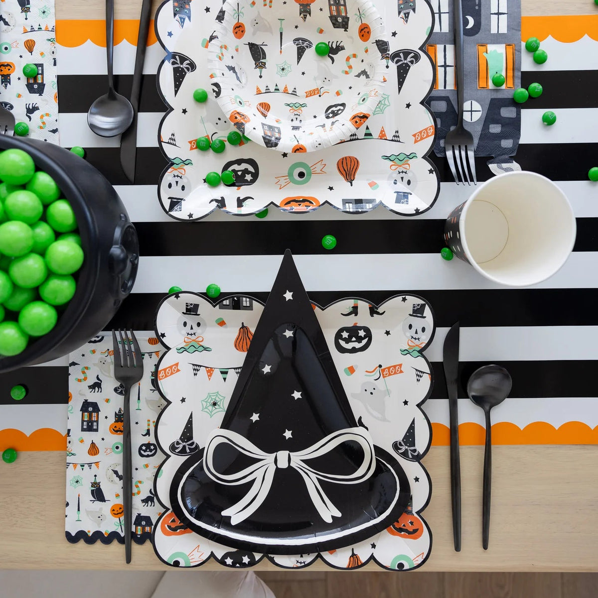 Flat-lay of square plate, coordinating bowl and striped table runner decorated for Halloween.
