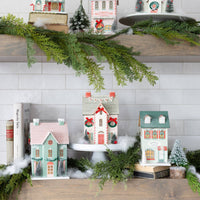 Close-up of the top shelf of the lighted Christmas village, featuring a church and several Christmas putz house designs.