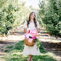 woman holding picnic basket with cherry plates and flowers
