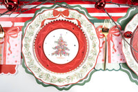 Place setting with the tree plate on scalloped red and evergreen-rim plates, gold cutlery, and a red bow napkin.