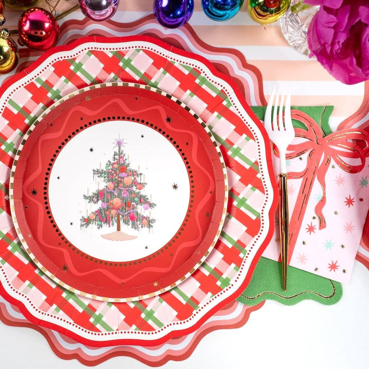 Place setting with the tree plate on a red plaid dinner plate and scalloped plate with a red bow.