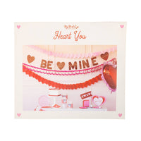 Triple heart tissue garlands hanging on Valentine party backdrop