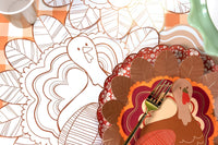 Overhead of the coloring placemat partially colored, showing the turkey with rust and orange feathers filled in and the uncolored outline.