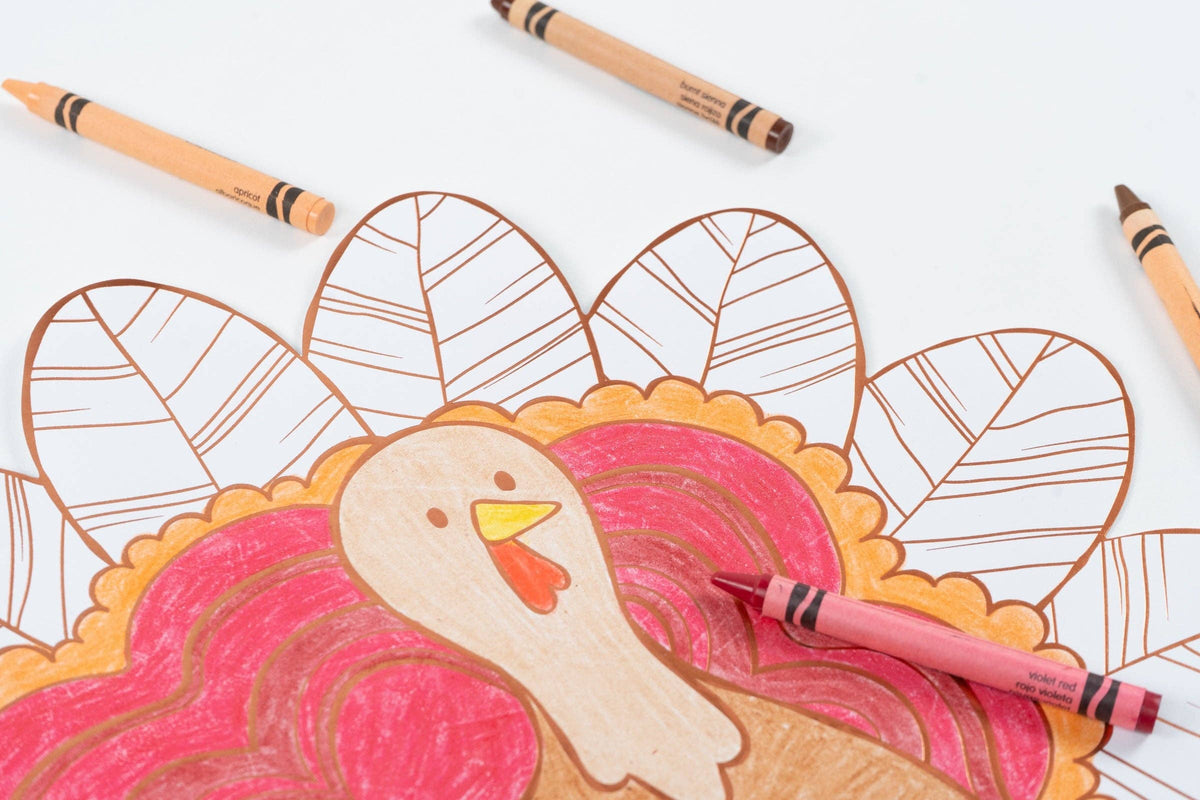 Close-up of the turkey coloring placemat showing a pink-and-orange colored turkey with markers beside it.