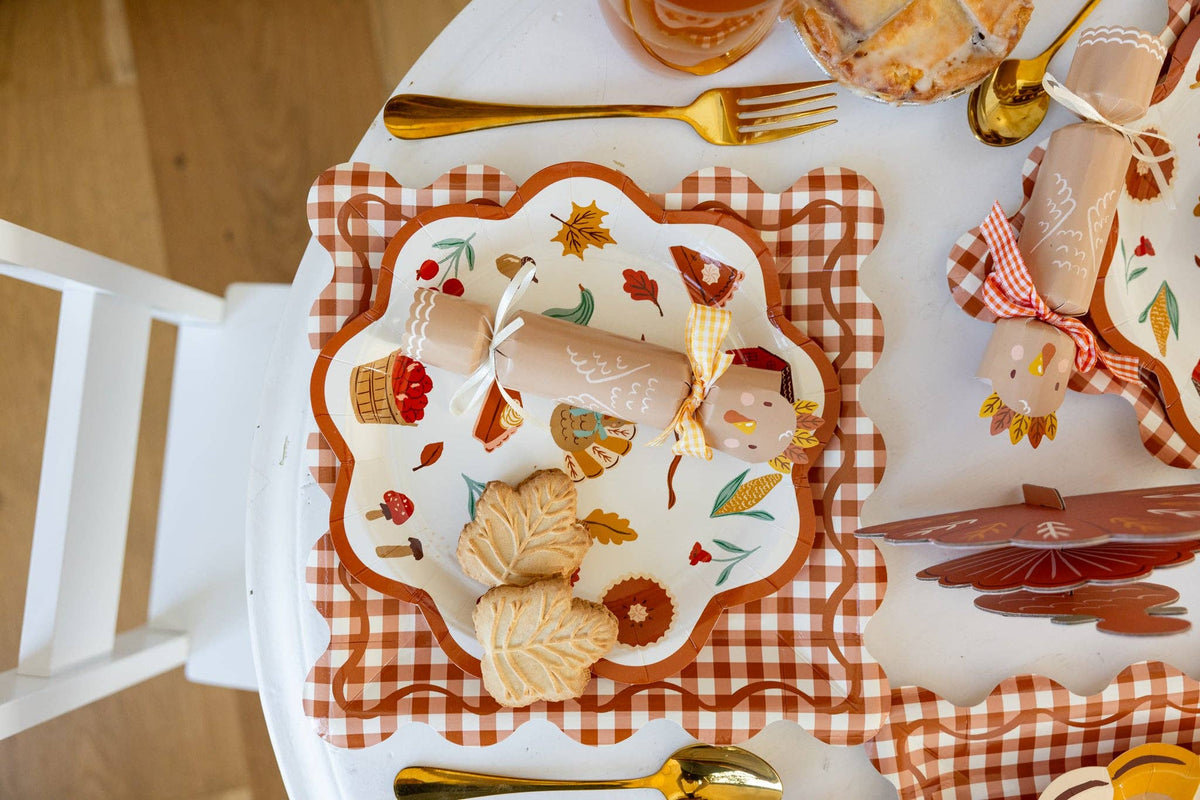 Decorative plate with autumn-themed design on a checkered tablecloth with gold cutler featuring the turkey crackers.