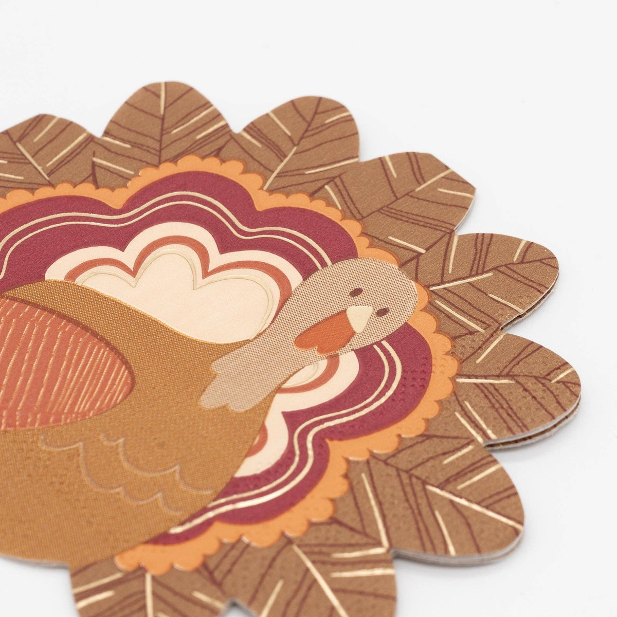 Two turkey shaped cocktail napkins overlapping at an angle, showing the die-cut turkey shape, layered feathers, and gold foil detail.