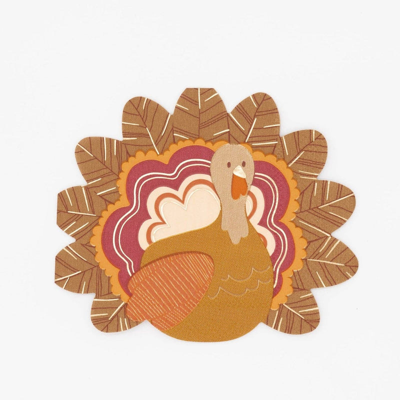 Die-cut turkey shaped Thanksgiving cocktail napkin with layered rust, burgundy, gold, and cream feathers and gold foil accents, front view on white background.