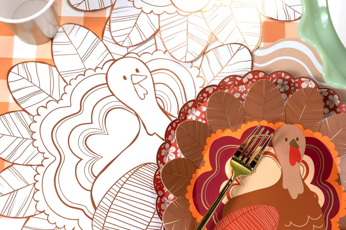 Overhead showing the turkey shaped plate beside turkey coloring placemats, with a partially colored turkey and a fall table.