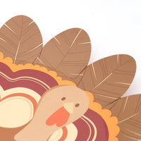 Angled view of the turkey shaped plate showing the die-cut turkey silhouette and layered feather detail.