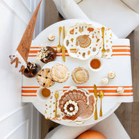 Thanksgiving tablescape featuring turkey plates with fall décor and desserts.