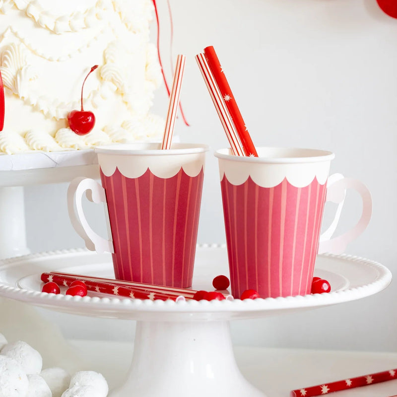 Two red paper cups with handles on a white cake stand, illustrating a beautiful festive table setting.	