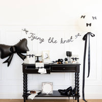 Full party setup featuring black bow balloon and Tying the Knot glitter banner