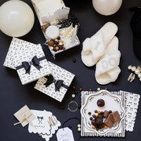 Flat lay of Tying the Knot gift setup with slippers, sweets, bow napkins, and treat boxes.