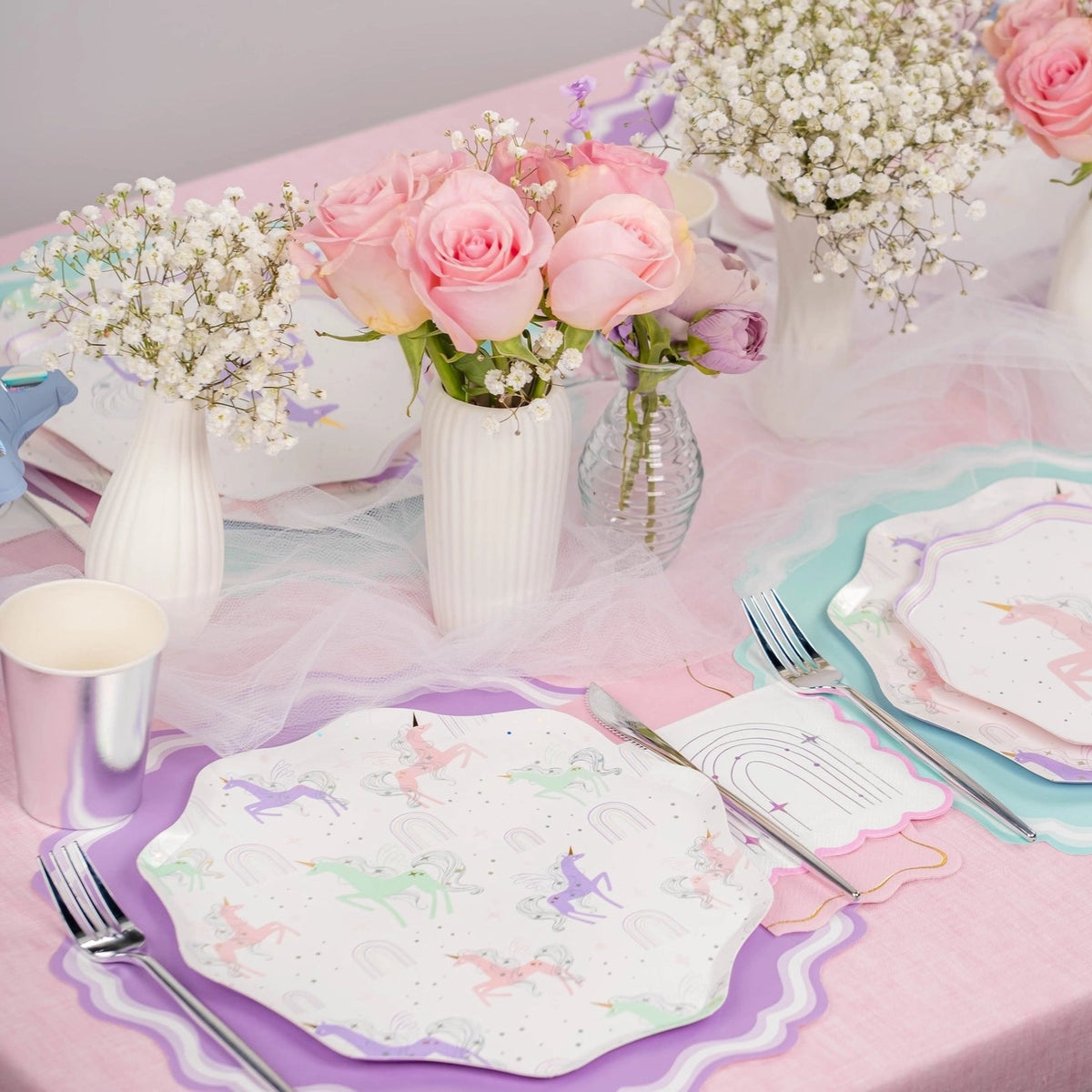 Place settings with mixed unicorn designs and rainbow napkins.