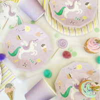 Overhead view of unicorn plates and cups with pastel party confetti