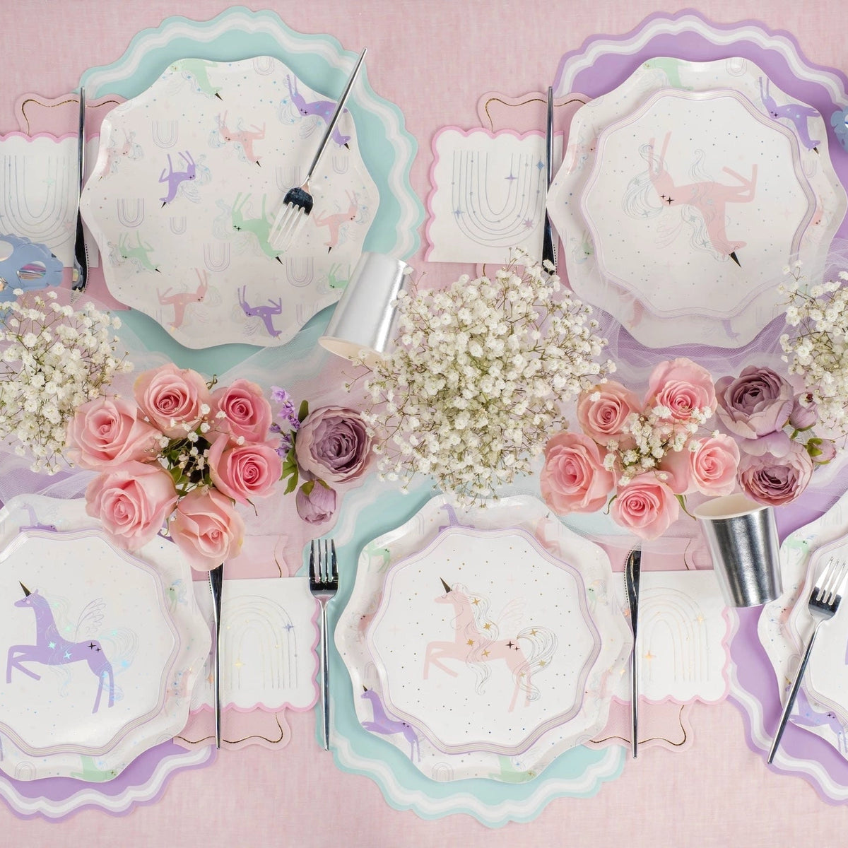 Place settings with mixed unicorn designs and rainbow napkins.