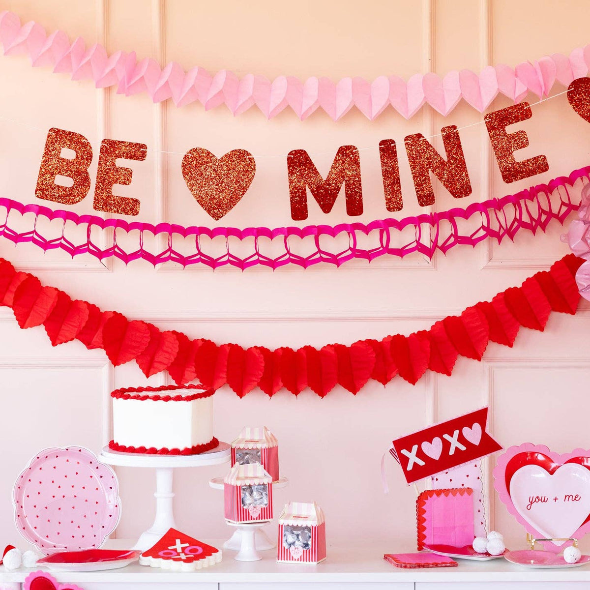 Layered Valentine party decor featuring triple heart garlands