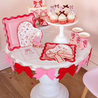Valentine’s Day table styled with bow shaped napkins, plates, and party decor