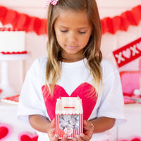 Child holding a Valentine kissing booth treat box filled with candy