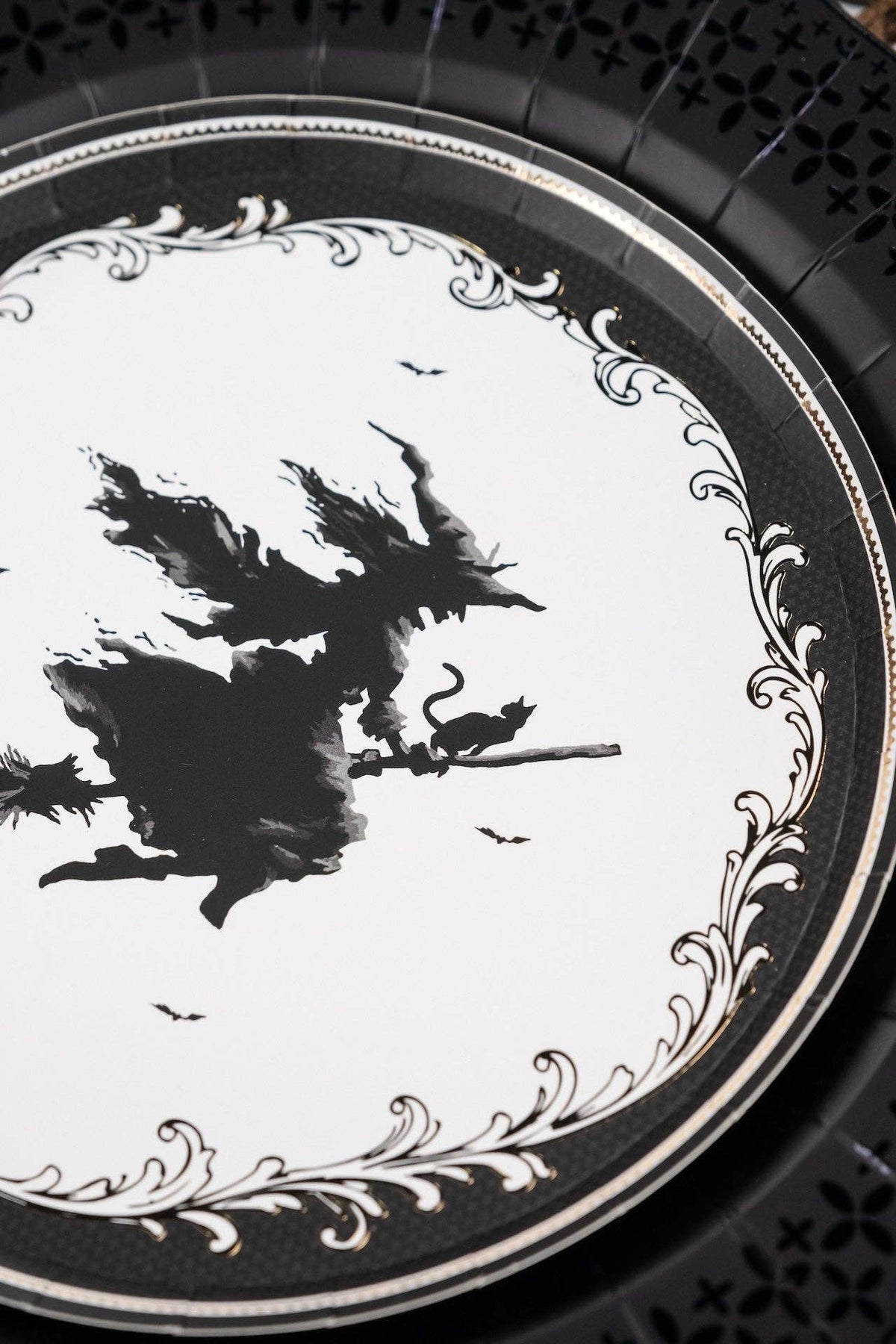 Close up vertical crop of the vintage witch silhouette plate layered neatly over an intricate matte black paper charger.