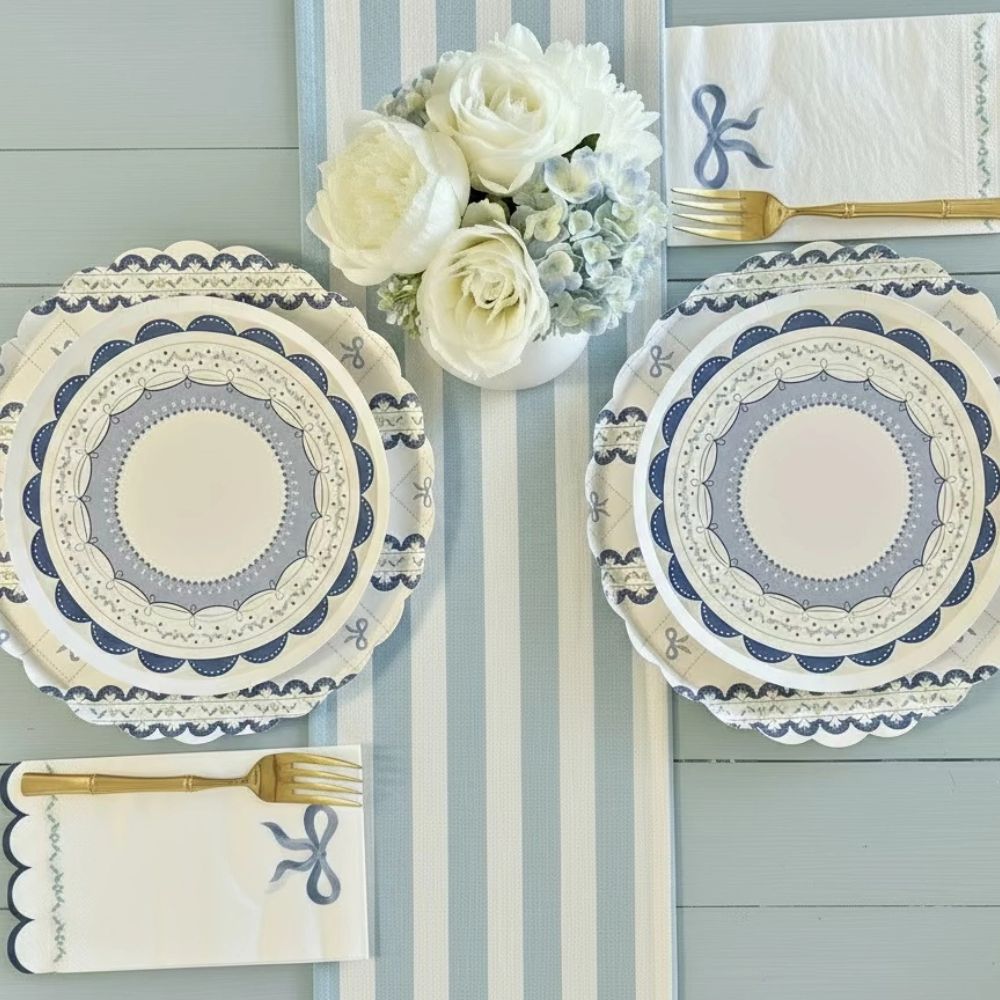 Blue bow napkins and plates styled with white roses and a blue striped runner